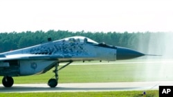 A Slovak Air Force MiG-29 goes through a water gate during an airshow in Malacky, Slovakia, Aug. 27, 2022.