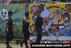 Polisi berjalan di depan mural kampanye Pemilu 2019 di Banda Aceh, 17 Maret 2019. (Foto: AFP/CHAIDEER MAHYUDDIN)