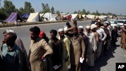 Displaced families line up to receive food after fleeing their flood-hit homes, in Charsadda, Pakistan, Aug. 29, 2022. International aid was reaching Pakistan on Monday, after widespread flooding driven by "monster monsoons" has claimed more than 1,000 lives since June.