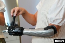 Jessica Smith, a former Australian Paralympic Swimmer, poses for a picture while applying make-up with her new bionic hand that improves the speed of movement and sensitivity of touch, according to the company, in London, Britain August 12, 2022. (REUTERS)