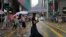 People wearing face masks, walk in the rain in Hong Kong, Tuesday, Aug. 9, 2022. 
