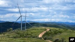 Tourists ride horses near Wind turbines on the grassland in Zhangbei county, in north China's Hebei province on Aug. 15, 2022. 