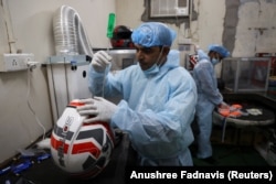 Seorang karyawan Shellios Technolabs, yang memproduksi helm sepeda motor yang dilengkapi dengan filter dan kipas di bagian belakang helm, sedang merakit helm di New Delhi, India, 23 Agustus. 2022. (Foto: REUTERS/Anushree Fadnavis)