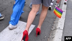 FILE - A participant holding a gay pride flag walks in high heels during a pride march, in Belgrade, Serbia, September 18, 2021. 