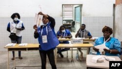 Une responsable électorale brandit un bulletin de vote dans un bureau de vote à Luanda le 24 août 2022.