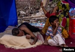 FILE - A Rohingya refugee family rests in a temporary shelter after a fire destroyed a Rohingya refugee camp on Saturday night, in New Delhi, India, June 14, 2021. (REUTERS/Danish Siddiqui)
