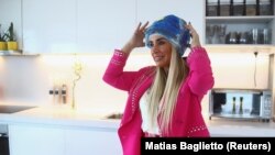 Mantan pasien kanker Paula Estrada menunjukkan helm darurat dari kantong es yang dibuatnya untuk mencegah kerontokan rambut selama kemoterapi, di Buenos Aires, Argentina, 23 Juni 2022. (Foto: REUTERS/Matias Baglietto)