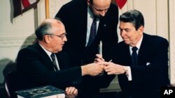 Pemimpin Uni Soviet Mikhail Gorbachev dan Presiden AS Ronald Reagan bertukar pena selama upacara penandatanganan Perjanjian Intermediate-Range Nuclear Forces (INF) di Gedung Putih, Washington, DC, 8 Desember 1987.