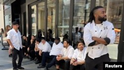 Kitchen staff wait outside a restaurant during a power outage in Toronto, Canada, Aug. 11, 2022.