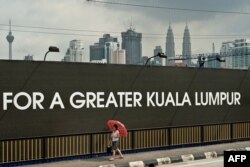 (FILES) Seorang perempuan berjalan melewati lokasi konstruksi 1 Malaysia Development Berhad (1MDB) unggulan Tun Razak Exchange di Kuala Lumpur, 3 Juli 2015. (Manan VATSYAYANA / AFP)