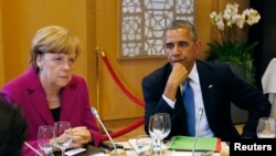 FILE - U.S. President Barack Obama (R) and German Chancellor Angela Merkel listen during the G7 Summit working dinner in Brussels.