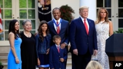 ประธานาธิบดีโดนัลด์ ทรัมป์ สุภาพสตรีหมายเลขหนึ่ง เมลาเนีย ทรัมป์ และไทเกอร์ วู้ดส์ ถ่ายภาพร่วมกับเอริกา เฮอร์แมน แฟนสาวของวูดส์ กุลธิดา วู้ดส์ มารดาของเขา และแซม อเล็กซิส วูดส์ และชาร์ลี แอ็กเซล วูดส์ ลูก ๆ ของเขา เมื่อ 6 พฤษภาคม 2019