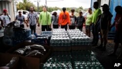 Volunteers and evacuees hold in hands while praying before serving dinner at a makeshift donation center Tuesday, May 8, 2018, in Pahoa, Hawaii. 