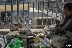 FILE - Afghan currency exchange dealers carry out their tasks after the money exchange market reopens for business in Kabul, Sept. 5, 2021.