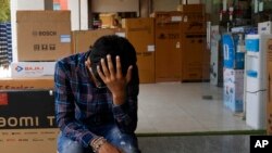 FILE - Sahil Rajput, 21, sits outside an electronic shop where he works in Rohtak, India, July 18, 2022.