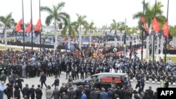 Le cortège transportant la dépouille de l'ancien président angolais José Eduardo dos Santos jusqu'à sa dernière demeure marche derrière le corbillard lors de ses funérailles d'État à la Praca da Republica à Luanda le 28 août 2022. 