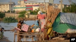 A Pakistani family look for salvageable belongings from their flood-hit home, in Sohbat Pur city of Jaffarabad, a district of Pakistan's southwestern Baluchistan province, Sunday, Aug. 28, 2022.
