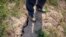 A farmer stands above a deep crack in the dried mud of an earthen embankment in his rice fields on the outskirts of Chongqing, China, Aug. 21, 2022.