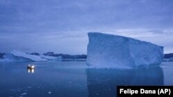 FILE - A boat navigates at night next to large icebergs in eastern Greenland on Aug. 15, 2019. Ice from Greenland's ice sheet will eventually raise global sea level by at least 27, according to a study released Monday, Aug. 29, 2022. (AP Photo/Felipe Dana, File)