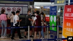 Seorang petugas dari sebuah maskapai meminta para penumpang untuk melaporkan informasi kesehatannya setelah check-in di Bandara Internasional Beijing, Rabu, 24 Agustus 2022. (Foto: AP)
