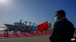Seorang pekerja pelabuhan Sri Lanka memegang bendera nasional China untuk menyambut kapal penelitian China Yuan Wang 5 saat tiba di Pelabuhan Internasional Hambantota di Hambantota, Sri Lanka, Selasa, 16 Agustus 2022. (Foto: AP)