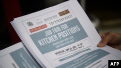 FILE - An employer holds flyers for hospitality employment during a Zislis Group job fair at The Brew Hall in Torrance, Calif., June 23. 2021.