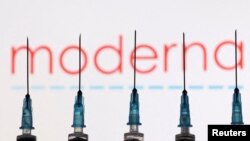 FILE - Syringes with needles are seen in front of a displayed Moderna logo in this illustration taken Nov. 27, 2021. 
