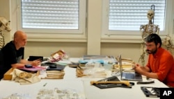 In this photo provided by the University of Poitiers in August 2022, researchers Franck Guy, left, and Guillaume Daver sit together at the PALEVOPRIM laboratory in Poitiers, France. (PALEVOPRIM/CNRS – Universite de Poitiers via AP)