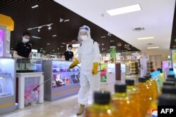 Seorang anggota staf melakukan disinfektan untuk menghentikan penyebaran COVID-19 di sebuah toko di Pyongyang. (Foto: AFP)