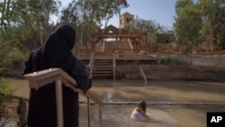 Olga Bokkas, a visitor from Connecticut, immerses herself in the waters of the Jordan River at the Qasr al-Yahud baptismal site, near the West Bank town of Jericho on Sunday, July 31, 2022. (AP Photo/Oded Balilty)