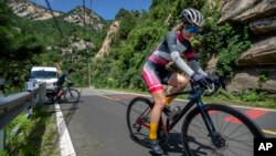 Members of the Qiyi bicycle club climb a hill on a rural road during a group ride through the Baihe River Canyon in the northern outskirts of Beijing, Wednesday, July 13, 2022. (AP Photo/Mark Schiefelbein)