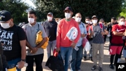 FILE - Migrants, some holding Red Cross blankets, are seen after arriving at Union Station, near the U.S. Capitol, from Texas on buses, in Washington, April 27, 2022.