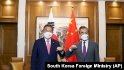 Menteri Luar Negeri Korea Selatan Park Jin (kiri) dan Menteri Luar Negeri China Wang Yi melakukan salam siku saat bertemu di Qingdao, China, pada 9 Agustus 2022. (Foto: South Korea Foreign Ministry via AP)
