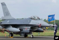 A Taiwanese Air Force flag bearer passes by one of the newly commissioned upgraded F-16V fighter jets at Air Force base in Chiayi in Taiwan, Nov. 18, 2021.