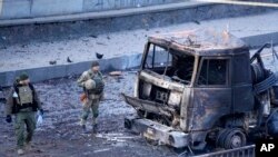 Ushtarët ukrainas duke inspektuar një mjet ushtarak rus të shkatërruar (26 shkurt 2022)