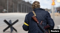 A member of the Territorial Defence Forces of Ukraine stands guard at a checkpoint on the outskirts of Kyiv, Ukraine, Feb. 27, 2022. 