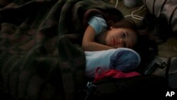 A child from Ukraine rests in a tent, part of a humanitarian center for refugees at the Moldovan-Ukrainian border, in Palalanca, Moldova, Feb. 25, 2022. Thousands of Ukrainians are fleeing from war by crossing their borders to the west in search of safety.