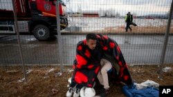 Pengungsi dari Ukraina tampak berusaha menghangatkan diri mereka saat menunggu di Siret, Rumania, wilayah perbatasan antara Ukraina dan Rumania, pada 28 Februari 2022. (Foto: AP/Andreea Alexandru))