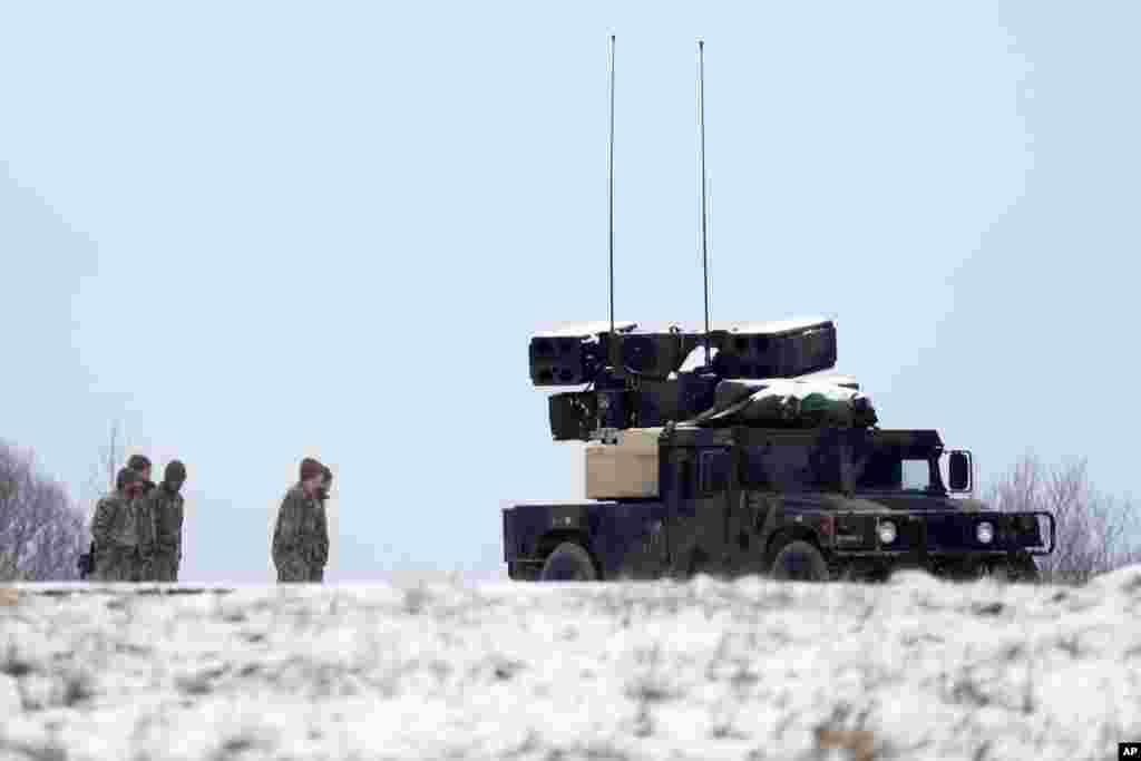 U.S. soldiers with military vehicles gather at a local airport in Arlamow, southeastern Poland, near the border with Ukraine, Feb. 28, 2022. President Vladimir Putin dramatically escalated East-West tensions by ordering Russian nuclear forces put on high alert.