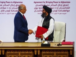 FILE - Mullah Abdul Ghani Baradar, leader of the Taliban delegation, and Zalmay Khalilzad, U.S. envoy for peace in Afghanistan, shake hands after signing an agreement between Afghanistan's Taliban and the U.S. in Doha, Qatar, Feb. 29, 2020.