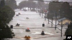 Warga menggunakan perahu kecil untuk melintasi banjir di Lismore, Australia, Senin, 28 Februari 2022. (Foto: via AP)