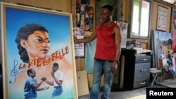 Ghanaian movie poster artist, Daniel Anum Jasper, 54, stands next to a hand-painted poster commissioned for a foreign client at his workshop in Accra, Ghana February 11, 2022. (REUTERS/Francis Kokoroko)