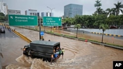 FILE - A military truck drives through the water on a flooded toll road following heavy rains in Jakarta, Indonesia, Saturday, Feb. 20, 2021. (AP Photo/Dita Alangkara, File)