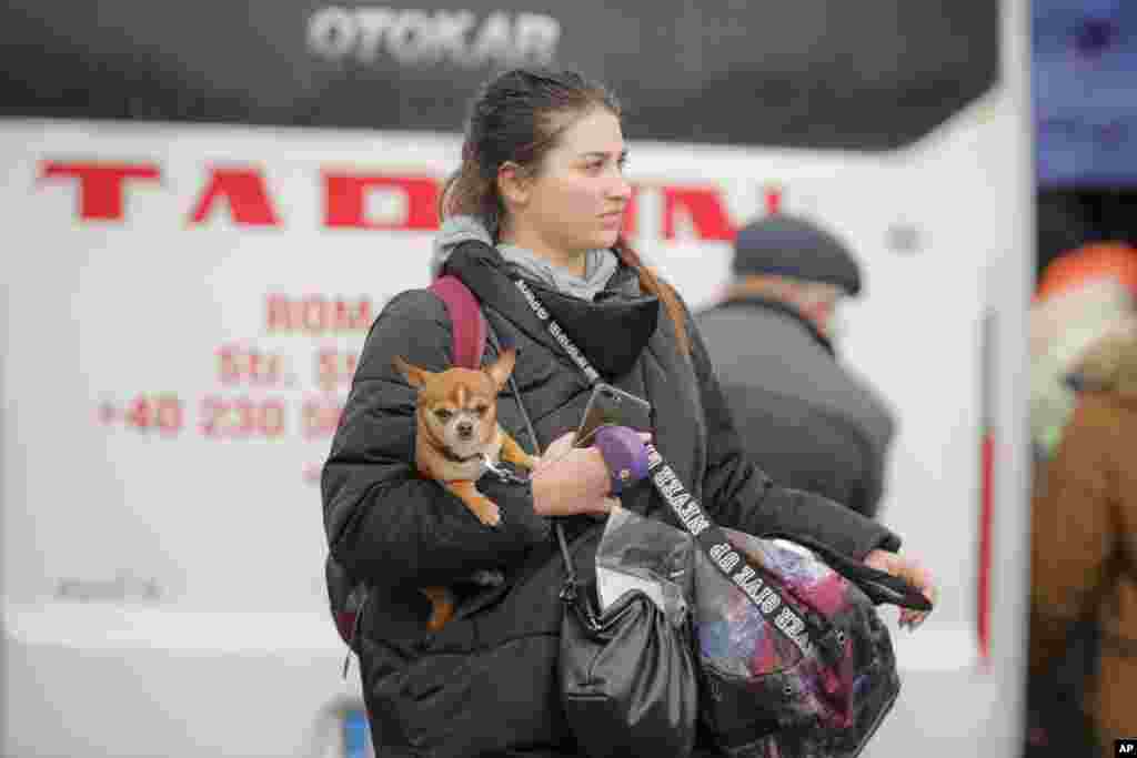 A refugee who fled the conflict from neighboring Ukraine carries a dog at the Romanian-Ukrainian border, in Siret, Romania, Feb. 27, 2022. 