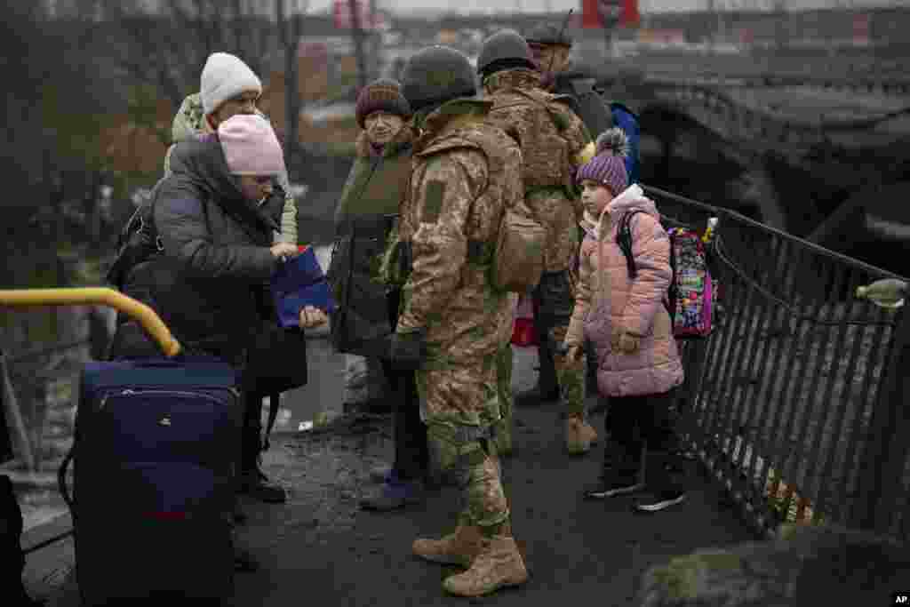 Ukrainian soldiers check people&#39;s identity cards as they flee their neighborhoods, on the outskirts of Kyiv, March 2. 2022.