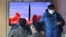 People watch a television screen showing a news broadcast with file footage of a North Korean missile test, at a railway station in Seoul on Feb. 27, 2022. 