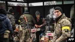 A woman cooks for Ukrainian soldiers at a frontline, northeast of Kyiv on March 3, 2022.