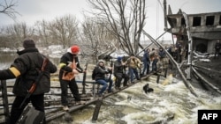 Para anggota pertahanan sipil Ukraina membagi-bagikan senjata kepada warga sipil lainnya di sebuah jembatan yang hancur akibat serangan artileri Rusia di Kyiv (foto: dok).