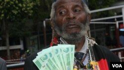 Holding bills of new Zimbabwean money, a man welcomes the introduction of 'bond notes' saying the move will ease cash shortages in the country, in Harare, Zimbabwe, Nov. 28, 2016. (S. Mhofu/VOA)