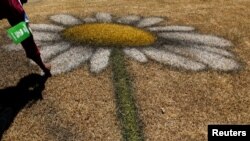 A person touches a land art created by French-Swiss land artist Guillaume Legros (Saype), invented from an eco-responsible paint composed mainly of chalk and charcoal, on the lawns of the UNEP in Gigiri, Nairobi, March 3, 2022. 